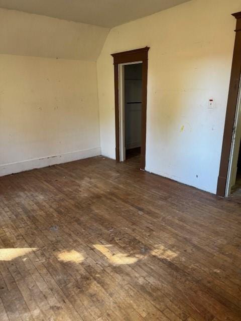 spare room featuring lofted ceiling and dark hardwood / wood-style flooring