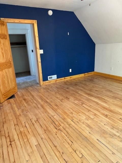 additional living space featuring ceiling fan, light wood-type flooring, and vaulted ceiling