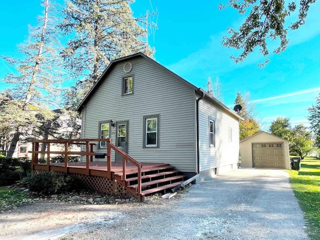 rear view of house featuring a garage, a wooden deck, and an outbuilding