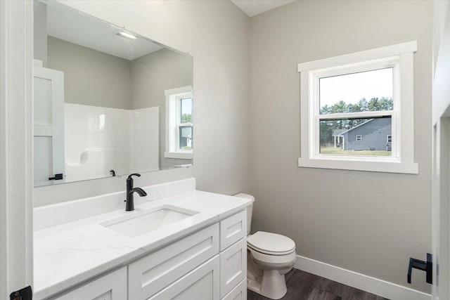 bathroom featuring a wealth of natural light, hardwood / wood-style floors, vanity, and toilet