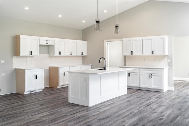 kitchen with high vaulted ceiling, a kitchen island with sink, hardwood / wood-style flooring, and white cabinetry