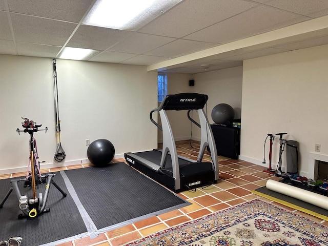 workout room featuring a paneled ceiling and tile patterned floors