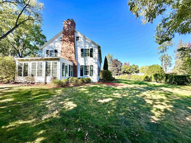 back of property featuring a lawn and a sunroom