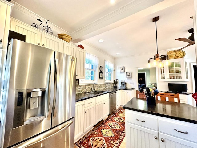 kitchen with hanging light fixtures, sink, ornamental molding, appliances with stainless steel finishes, and white cabinetry