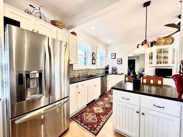 kitchen with appliances with stainless steel finishes, light wood-type flooring, sink, pendant lighting, and white cabinetry