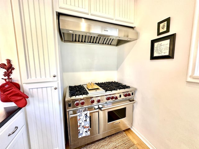 kitchen featuring range with two ovens, light wood-type flooring, and extractor fan