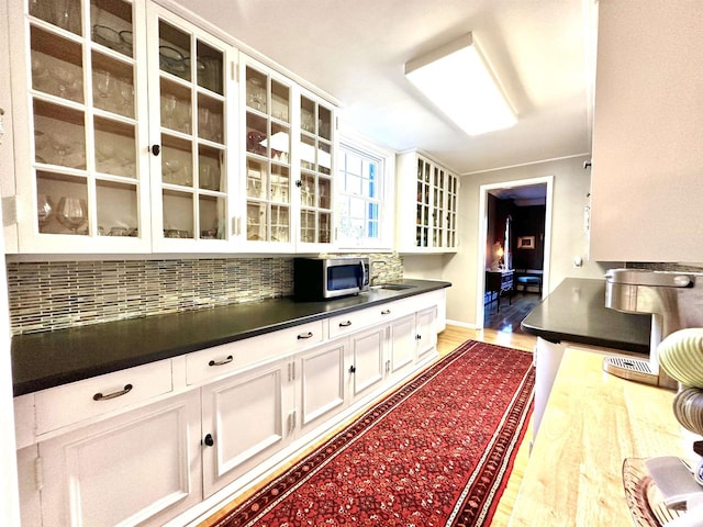 kitchen featuring sink, tasteful backsplash, white cabinetry, and light hardwood / wood-style flooring