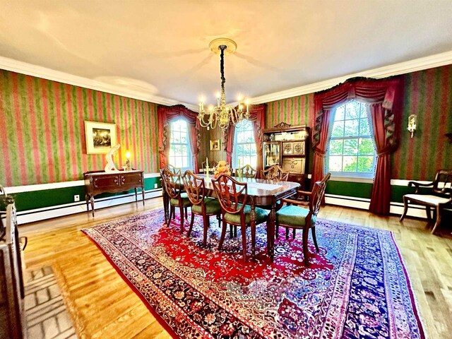 dining space featuring wood-type flooring, crown molding, baseboard heating, and a notable chandelier