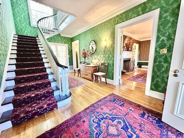 staircase with hardwood / wood-style floors, ornamental molding, and baseboard heating