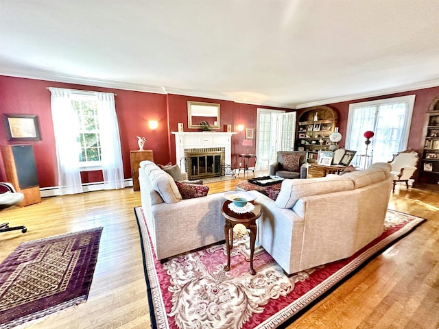 living room with light wood-type flooring, ornamental molding, baseboard heating, and a brick fireplace