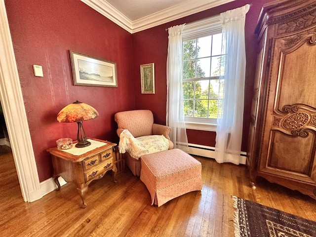 living area with wood-type flooring, ornamental molding, and a baseboard radiator