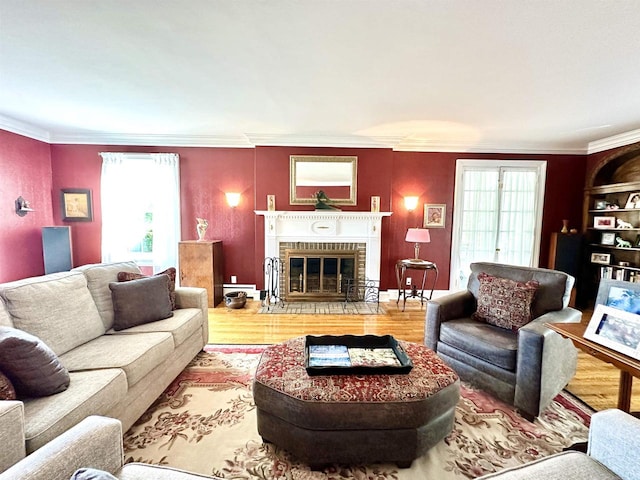 living room with light hardwood / wood-style floors, crown molding, and a brick fireplace