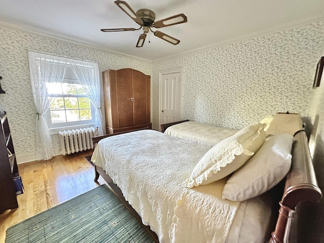 bedroom featuring radiator heating unit, ceiling fan, crown molding, and wood-type flooring