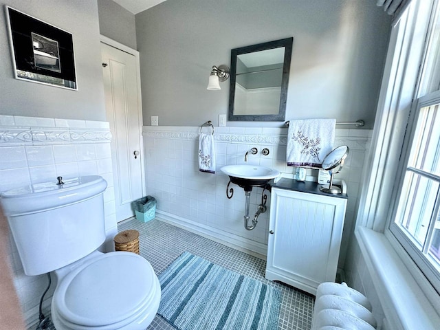 bathroom with radiator, sink, tile patterned floors, toilet, and tile walls