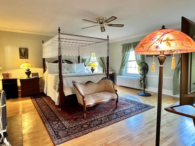 bedroom with radiator heating unit, hardwood / wood-style flooring, ceiling fan, and ornamental molding