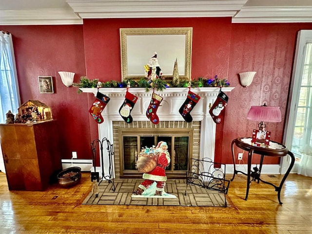 living area with crown molding, a fireplace, wood-type flooring, and a baseboard heating unit