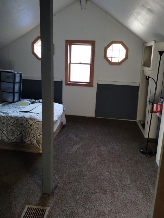 bedroom featuring lofted ceiling and dark colored carpet