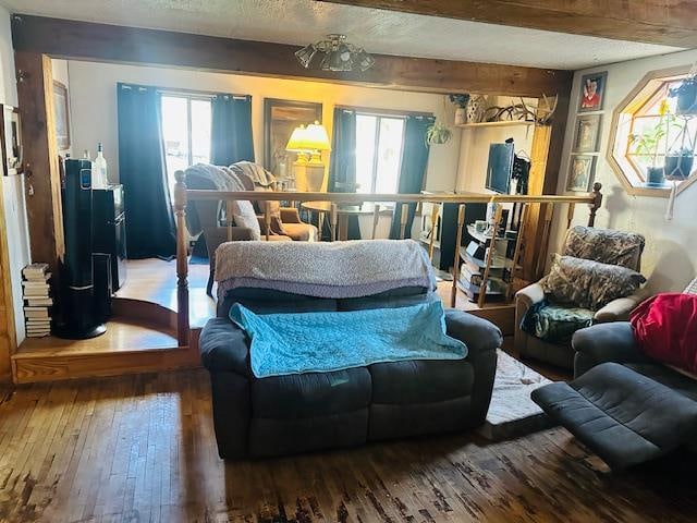 living area featuring beam ceiling, hardwood / wood-style flooring, and a textured ceiling