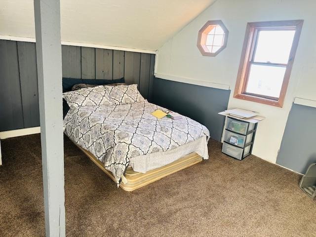 bedroom with lofted ceiling, wooden walls, and carpet flooring