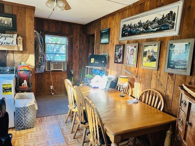 dining room featuring ceiling fan, cooling unit, wooden walls, and light parquet floors