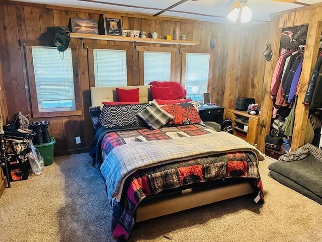 carpeted bedroom featuring wood walls and ceiling fan