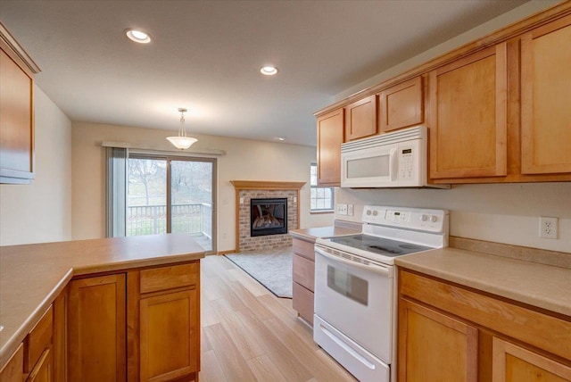 kitchen featuring white appliances, decorative light fixtures, light hardwood / wood-style floors, and a brick fireplace