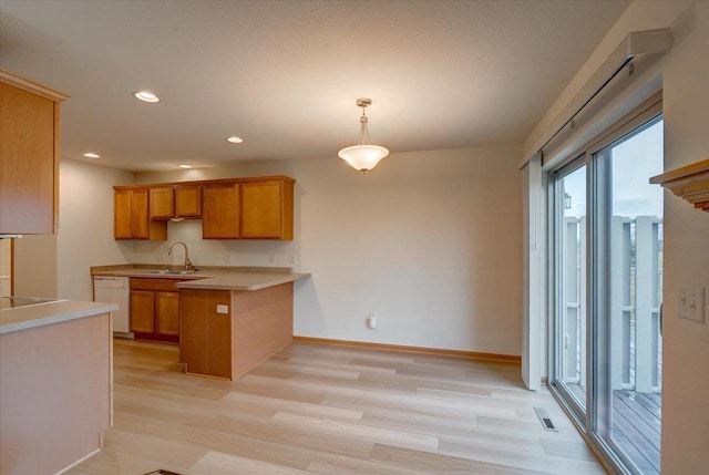 kitchen with light wood-type flooring, hanging light fixtures, sink, dishwasher, and kitchen peninsula