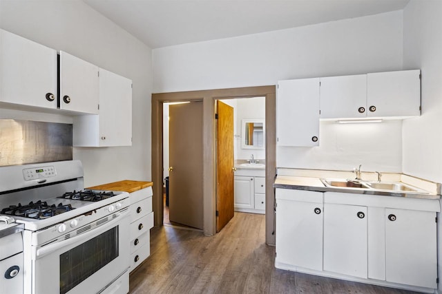 kitchen with white cabinets, sink, hardwood / wood-style floors, and white gas range oven