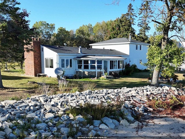 rear view of property featuring a sunroom and a lawn