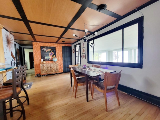 dining space with light hardwood / wood-style flooring and coffered ceiling