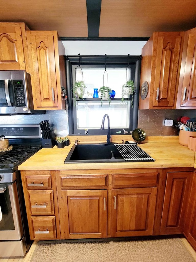 kitchen featuring wooden counters, stainless steel appliances, sink, and backsplash