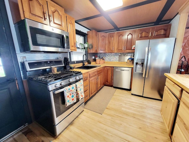 kitchen featuring appliances with stainless steel finishes, light hardwood / wood-style flooring, sink, and backsplash