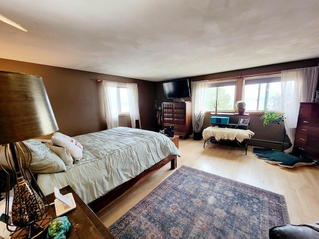 bedroom with light hardwood / wood-style flooring and a baseboard heating unit