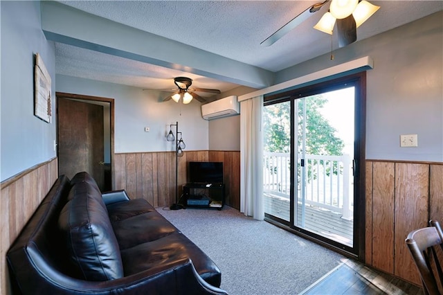 living room featuring ceiling fan, wood walls, a textured ceiling, carpet floors, and an AC wall unit