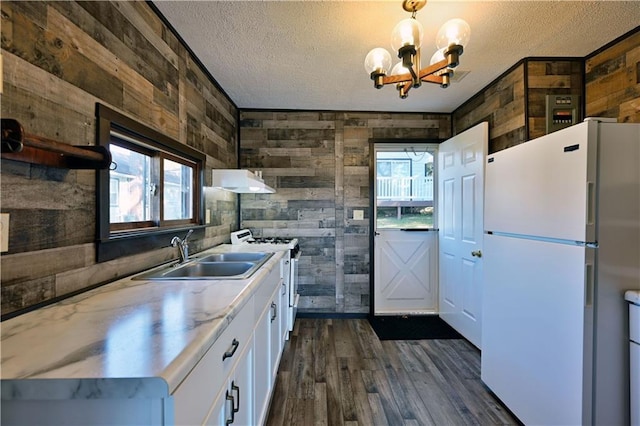 kitchen featuring white cabinets, wood walls, and white appliances