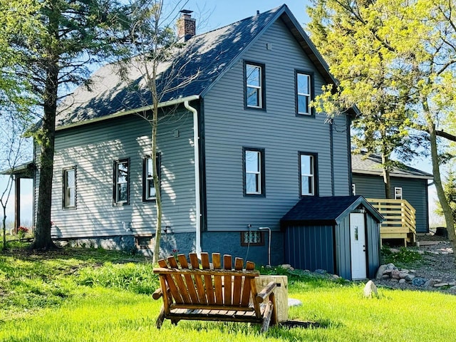 rear view of house with a yard and a storage shed