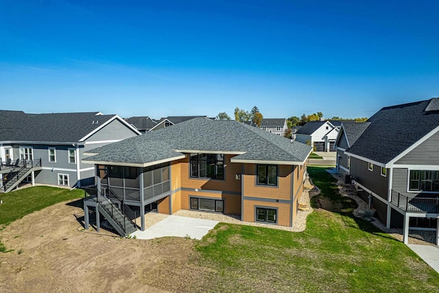 back of property featuring a lawn, a patio area, and a sunroom