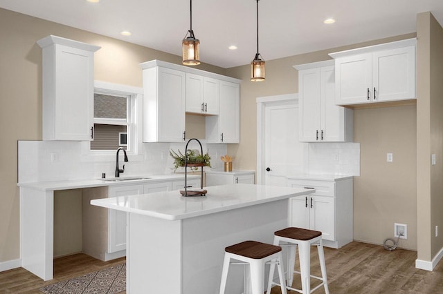 W4946 Battlestone Station Rd Unit 23, La Crosse, WI 54601 - kitchen featuring a center island, white cabinets, a sink, light wood-type flooring, and decorative backsplash