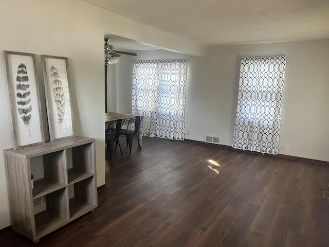 unfurnished dining area featuring dark wood-type flooring and ceiling fan