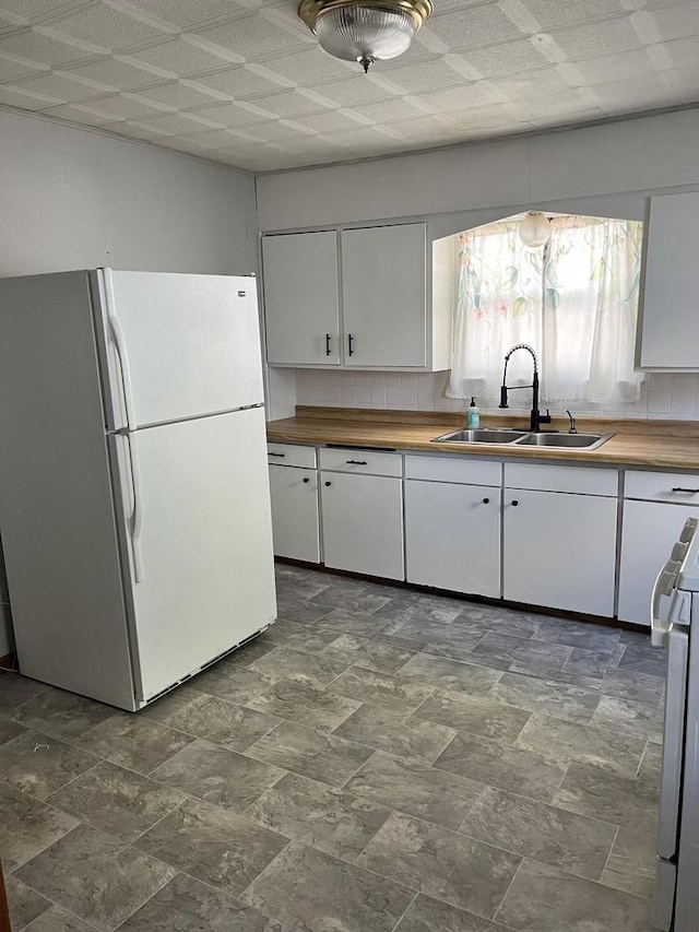 kitchen featuring butcher block countertops, sink, white appliances, and white cabinetry