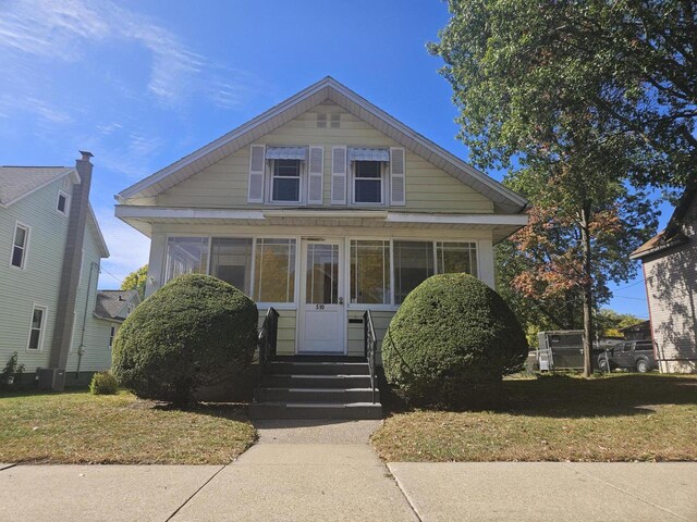 bungalow-style house with a sunroom and a front lawn