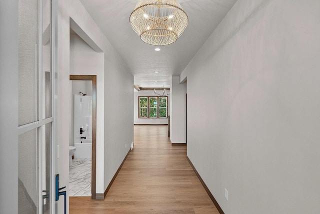 hall featuring light hardwood / wood-style floors and a notable chandelier