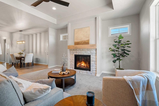 living room featuring ceiling fan, a fireplace, and light hardwood / wood-style flooring