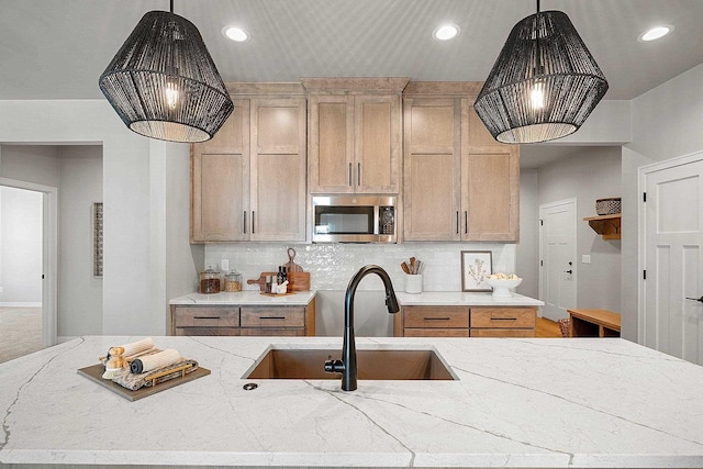 kitchen featuring light brown cabinetry, pendant lighting, decorative backsplash, and sink