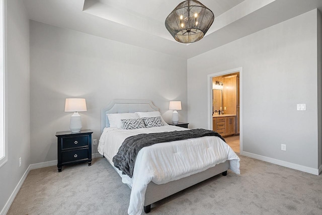 bedroom featuring a tray ceiling, carpet flooring, and ensuite bathroom