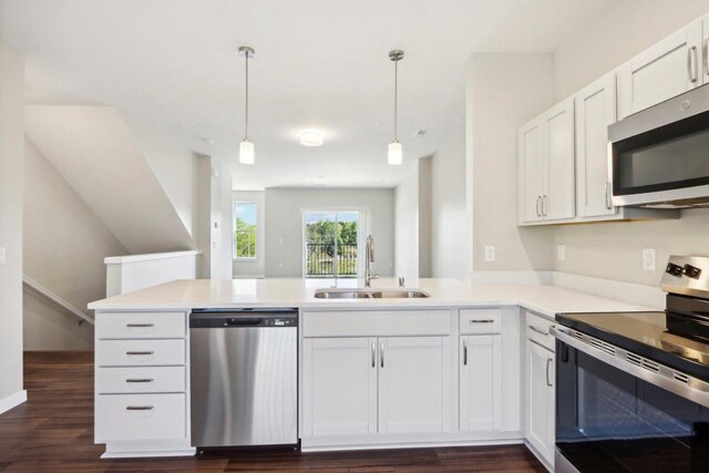 kitchen with pendant lighting, dark hardwood / wood-style flooring, stainless steel appliances, kitchen peninsula, and white cabinetry