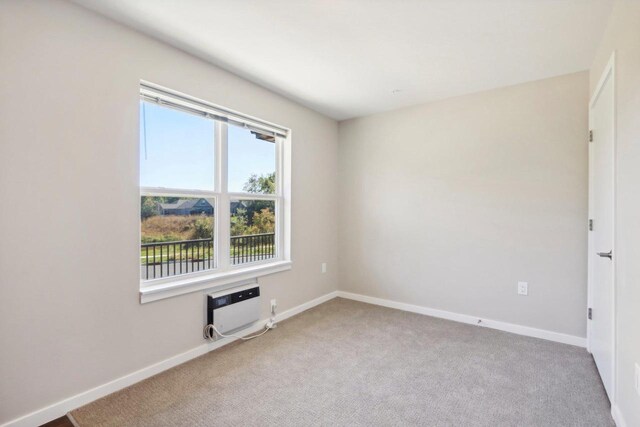 spare room with light colored carpet and a wall mounted air conditioner