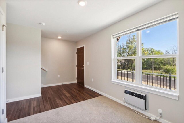 empty room featuring a wall mounted AC and dark hardwood / wood-style flooring