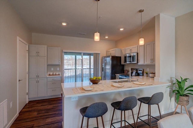 kitchen with a peninsula, a kitchen bar, light countertops, and appliances with stainless steel finishes
