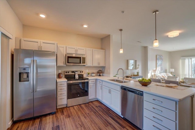 kitchen with a sink, open floor plan, light countertops, appliances with stainless steel finishes, and a peninsula